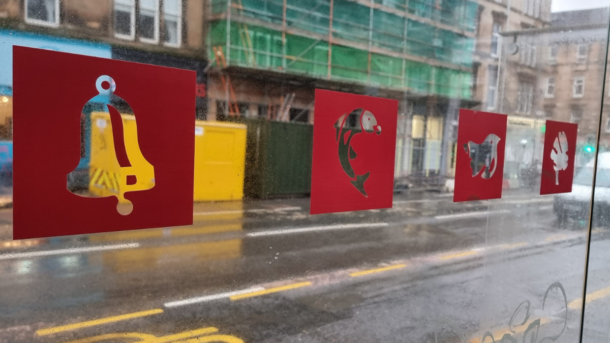 Pic of logos of a bell, a fish, a bird and a tree on Glasgow bus stop